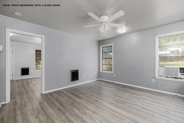 unfurnished living room with cooling unit, ceiling fan, light wood-type flooring, and heating unit