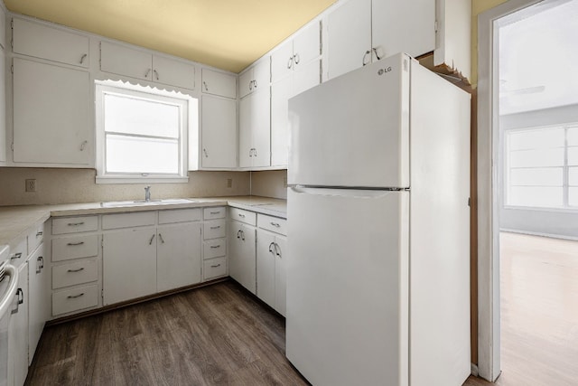 kitchen with dark wood-type flooring, white cabinets, white fridge, and sink