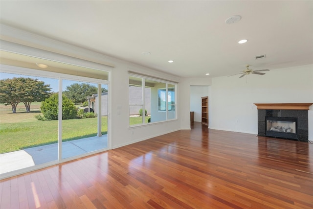 unfurnished living room with ceiling fan, hardwood / wood-style floors, and a tile fireplace