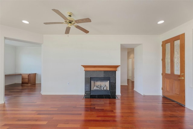 unfurnished living room featuring ornamental molding, dark wood-type flooring, a fireplace, and ceiling fan