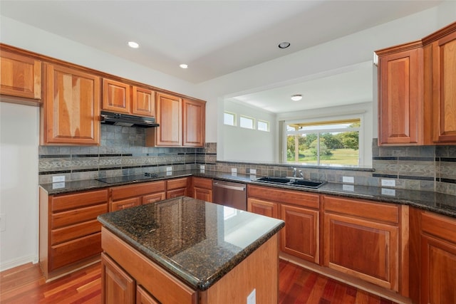 kitchen featuring a center island, dark hardwood / wood-style floors, dark stone counters, and stainless steel dishwasher