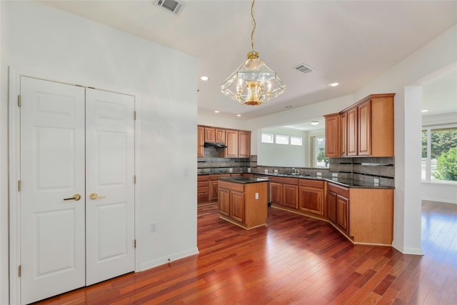 kitchen featuring dark hardwood / wood-style flooring, a chandelier, decorative light fixtures, and tasteful backsplash