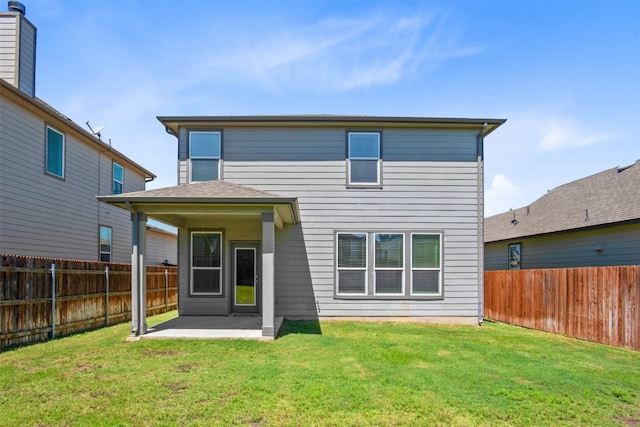 rear view of house featuring a lawn and a patio