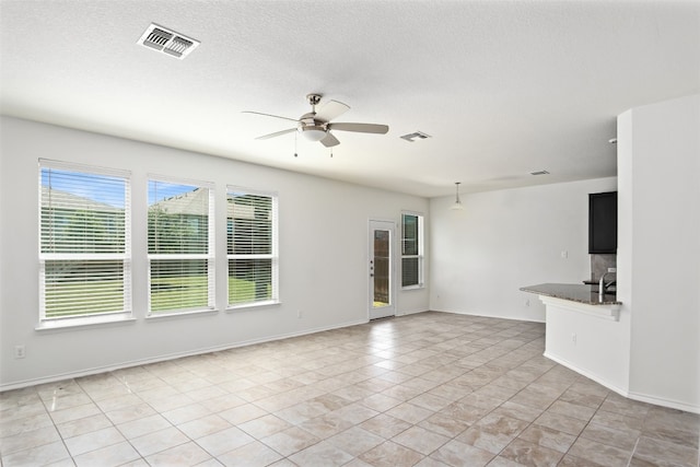 unfurnished living room featuring ceiling fan, a textured ceiling, and light tile patterned floors