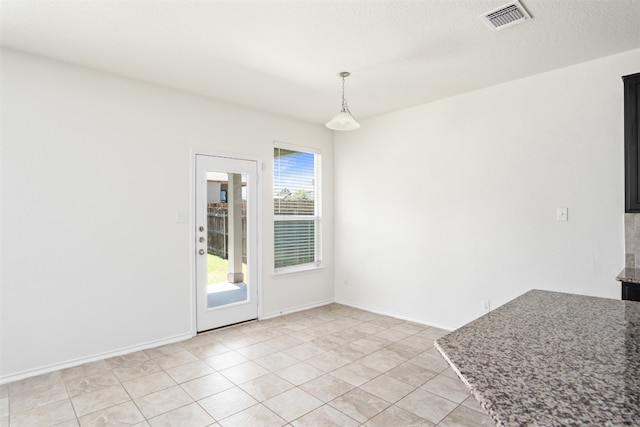 unfurnished dining area featuring a textured ceiling and light tile patterned floors