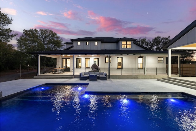 pool at dusk featuring an outdoor living space and a patio