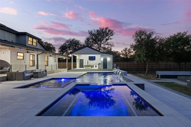 pool at dusk with pool water feature, a patio, and outdoor lounge area