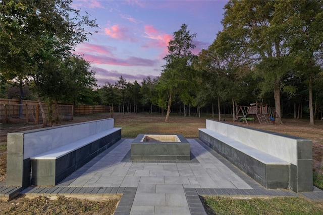 patio terrace at dusk featuring a fire pit and a playground