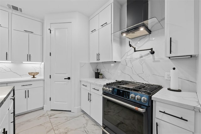 kitchen featuring tasteful backsplash, stainless steel gas range oven, and white cabinets