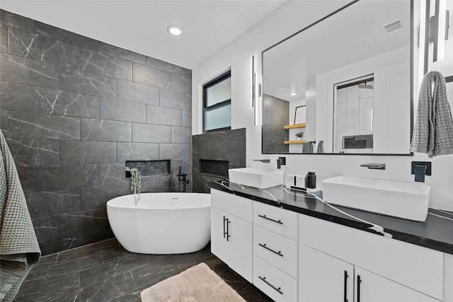 bathroom with a fireplace, vanity, tile walls, and a bathtub