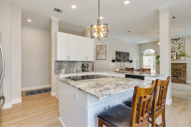 kitchen featuring light stone countertops, light hardwood / wood-style flooring, kitchen peninsula, black electric cooktop, and white cabinets