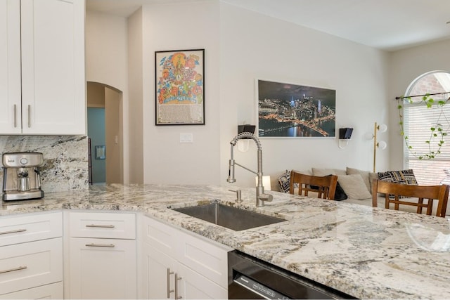 kitchen featuring backsplash, dishwasher, light stone countertops, white cabinetry, and sink