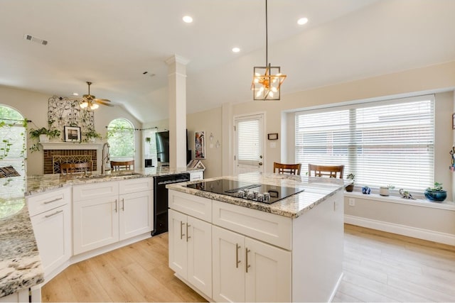 kitchen with vaulted ceiling, a fireplace, black appliances, light hardwood / wood-style flooring, and sink