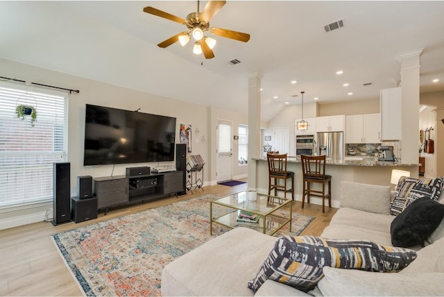 living room featuring lofted ceiling, light hardwood / wood-style flooring, ceiling fan, and decorative columns