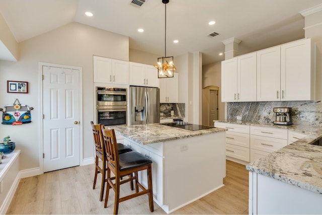 kitchen featuring a kitchen island, stainless steel appliances, hanging light fixtures, and white cabinets