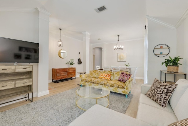 living room with crown molding, light hardwood / wood-style flooring, and ornate columns