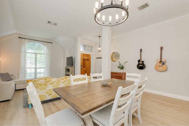 dining area with light wood-type flooring, lofted ceiling, a chandelier, and ornamental molding