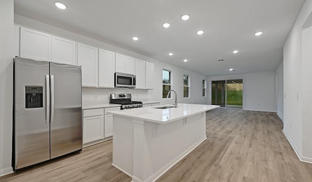 kitchen featuring sink, white cabinetry, stainless steel appliances, and an island with sink