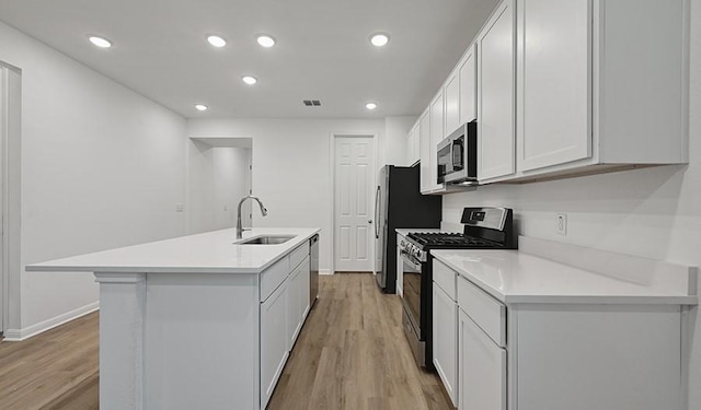 kitchen with white cabinetry, sink, an island with sink, light hardwood / wood-style floors, and appliances with stainless steel finishes