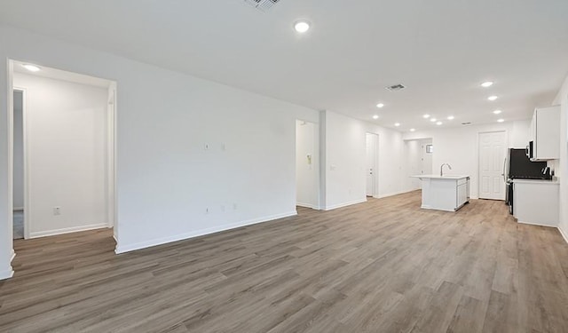 unfurnished living room featuring sink and light hardwood / wood-style floors