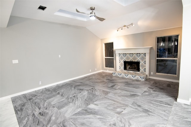 living room with ceiling fan, a tiled fireplace, and track lighting