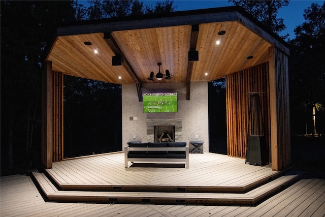 deck at twilight featuring exterior fireplace