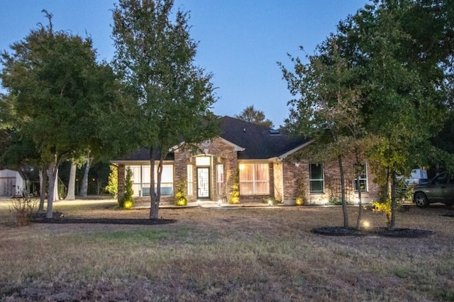 view of front of home with a storage shed and a yard