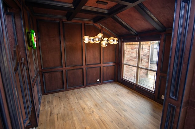 spare room featuring light wood-type flooring, beam ceiling, and wooden walls