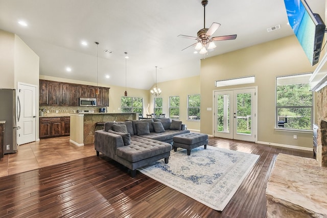 living room featuring dark wood-type flooring, ceiling fan with notable chandelier, and high vaulted ceiling