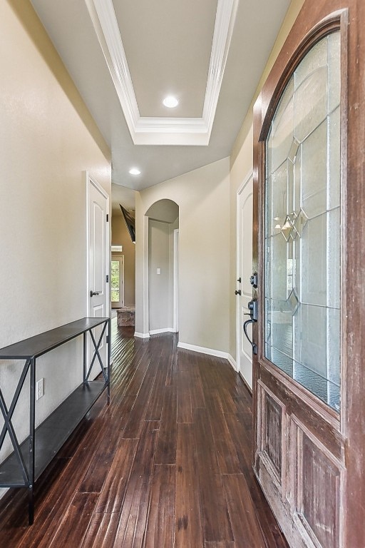 foyer featuring dark wood-type flooring, ornamental molding, and a tray ceiling