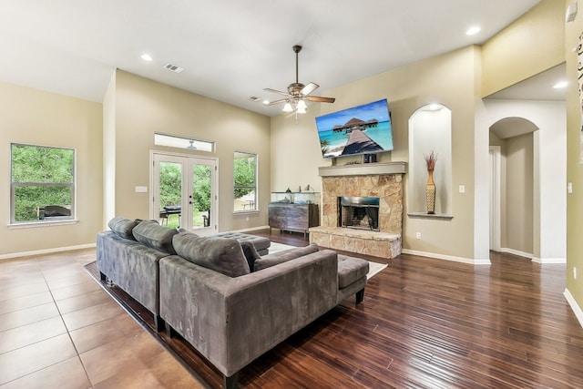 living room featuring a fireplace, dark wood-type flooring, french doors, and ceiling fan