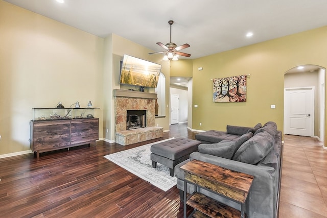 living room with dark wood-type flooring, ceiling fan, and a fireplace