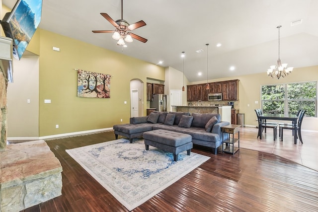 living room featuring ceiling fan with notable chandelier, dark hardwood / wood-style flooring, and high vaulted ceiling