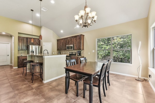 dining space featuring vaulted ceiling, an inviting chandelier, and sink