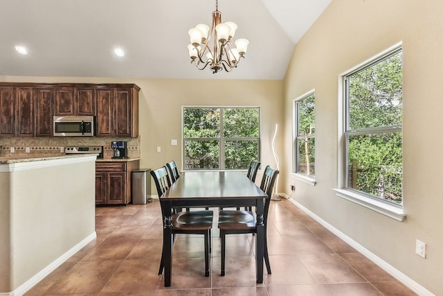 dining room featuring tile patterned flooring, plenty of natural light, vaulted ceiling, and an inviting chandelier