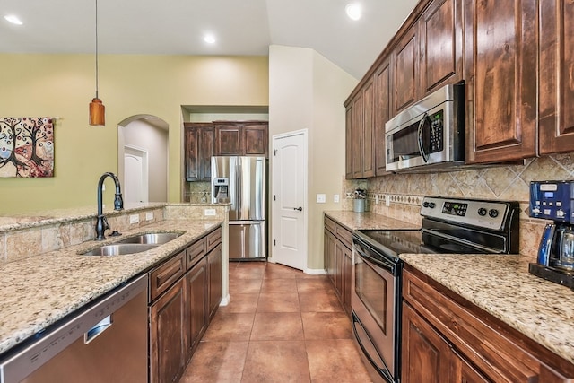 kitchen with pendant lighting, sink, light stone countertops, and appliances with stainless steel finishes