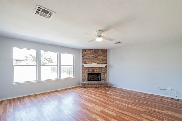 unfurnished living room with plenty of natural light, ceiling fan, light wood-type flooring, and a fireplace