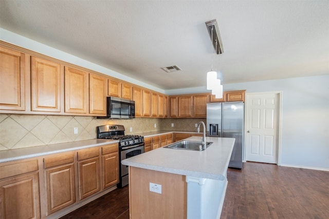 kitchen featuring decorative light fixtures, stainless steel appliances, dark hardwood / wood-style flooring, an island with sink, and sink