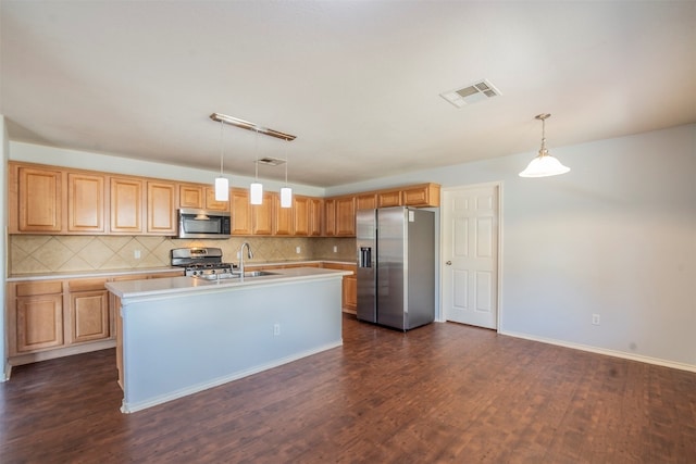 kitchen featuring dark hardwood / wood-style floors, decorative light fixtures, a center island with sink, backsplash, and stainless steel appliances