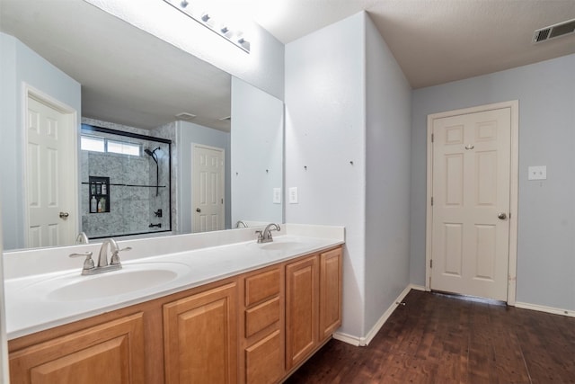 bathroom with wood-type flooring, a shower with door, a textured ceiling, and vanity