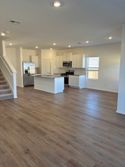 kitchen with sink, a center island with sink, appliances with stainless steel finishes, dark hardwood / wood-style flooring, and white cabinets