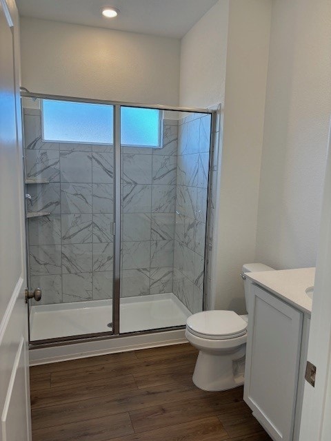 bathroom featuring vanity, wood-type flooring, toilet, and walk in shower