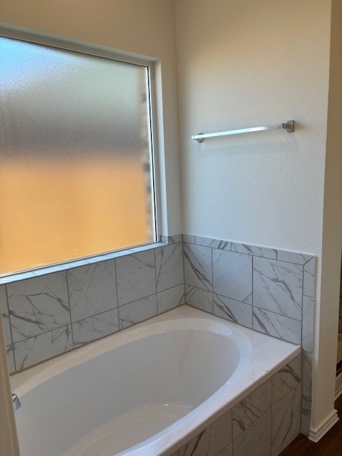 bathroom featuring hardwood / wood-style floors and tiled tub