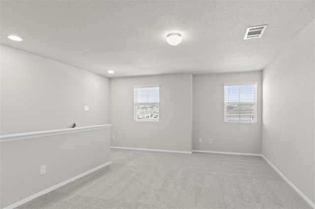 carpeted spare room with a textured ceiling and a wealth of natural light