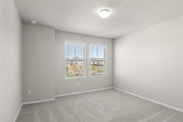 unfurnished room featuring a textured ceiling and light carpet