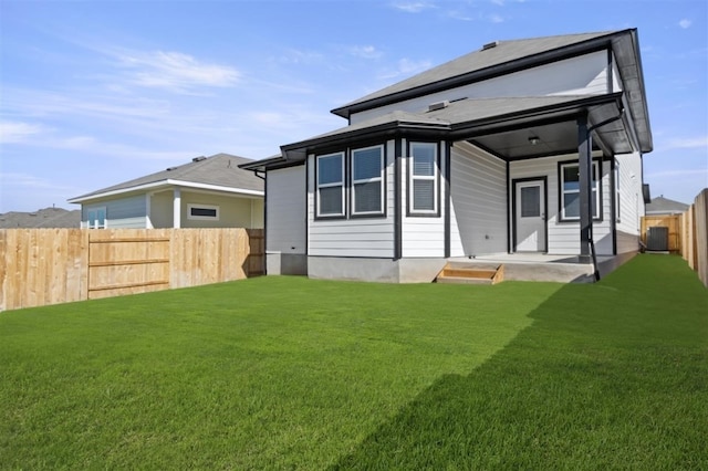 rear view of house with central AC and a yard