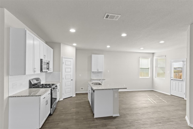 kitchen featuring white cabinets, a kitchen island with sink, light stone counters, and appliances with stainless steel finishes