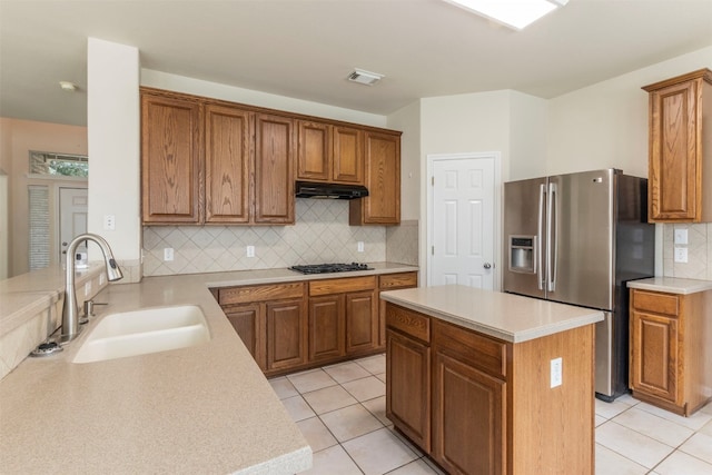 kitchen with light tile patterned flooring, sink, tasteful backsplash, a kitchen island, and appliances with stainless steel finishes