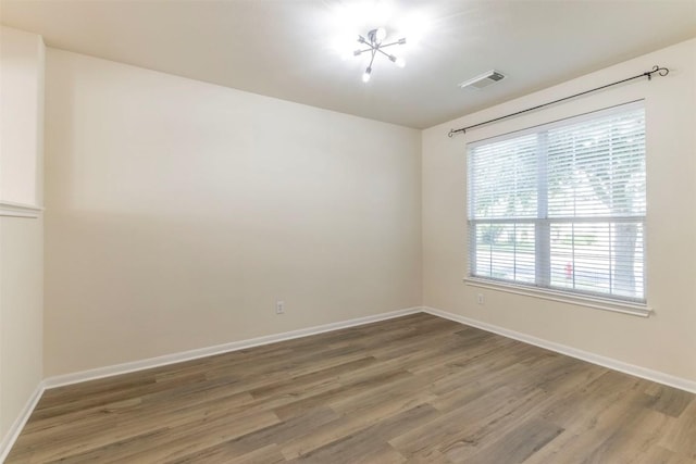 spare room with baseboards, light wood-type flooring, and visible vents