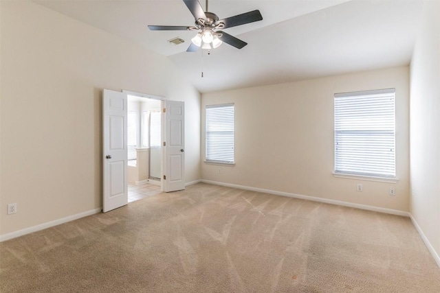 spare room with visible vents, lofted ceiling, light carpet, baseboards, and ceiling fan